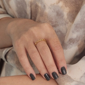 Detailed close-up of golden oval link chain ring showing polished metallic luster on finger