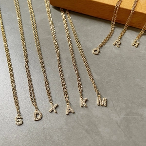 Detailed macro view of 14K gold plated initial pendants with micro-pave cubic zirconia