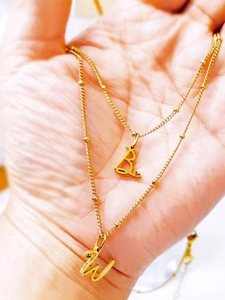 Gros plan d'un collier double épaisseur doré à perles avec pendentifs lettres B et W
