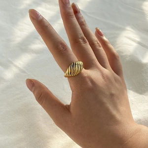 Vue détaillée d'une bague croissant dorée montrant la texture torsadée sur la main