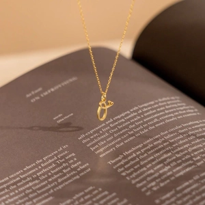Golden personalized alphabet heart pendant necklace with delicate chain on vintage book