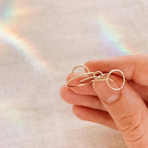 Macro shot of geometric double-loop stainless steel ring in gold finish on textured fabric