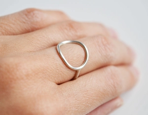 Detailed close-up of a minimalist hollow circular stainless steel ring on model finger