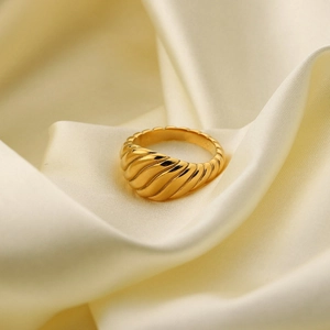 Bague torsadée en acier inoxydable doré poli sur un fond en soie élégant