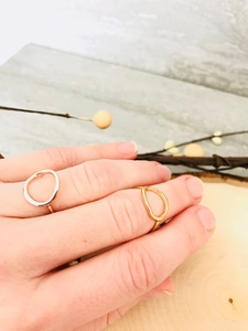 Detailed view of minimalist gold and silver irregular geometric rings on a wooden tray