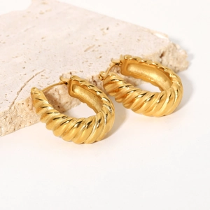 Close-up of golden twist croissant hoop earrings made of textured stainless steel