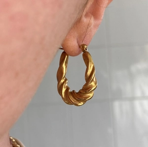Golden twisted hoop earrings in titanium steel featuring a textured geometric spiral design