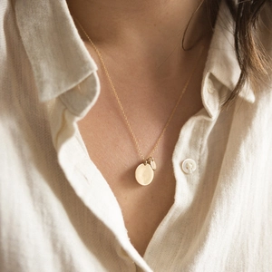 Minimalist double round pendant necklace in gold finish on a linen background