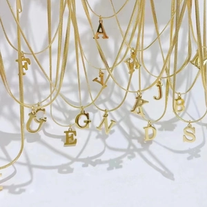 Detalle de collares de cadena de serpiente dorada con colgantes de letras A-Z pulidas