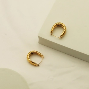 Detailed close-up of gold croissant hoop earrings with a twisted rope texture finish