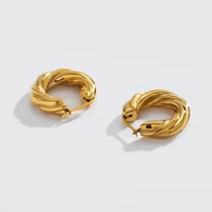 Détail de boucles d'oreilles torsadées dorées avec finition métallique polie