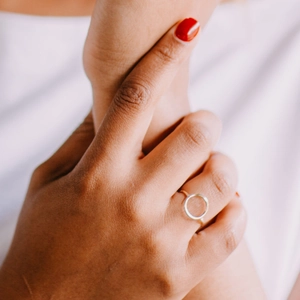 Close-up of a minimalist hollow geometric circular ring in silver on a female hand