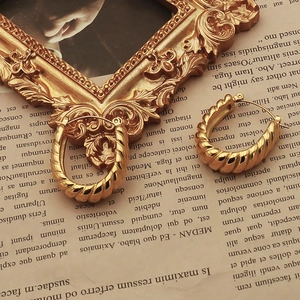Macro detail of gold croissant hoop earrings with elegant spiral texture on vintage frame