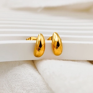 Macro view of polished gold teardrop stud earrings showing smooth mirror reflection