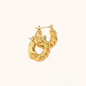 Close-up of twisted gold C-shaped hoop earrings with a liquid-like spiral texture