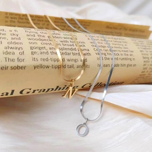 Detalle de los colgantes de letras N dorada y O plateada en cadenas de serpiente planas