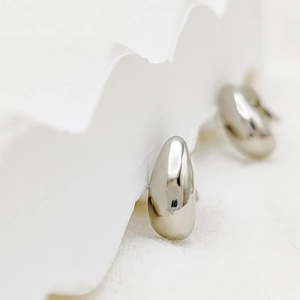 Detailed view of silver water drop earrings on white minimalist stone stand