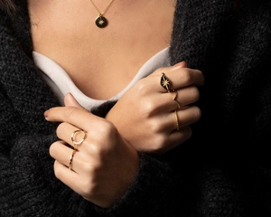 Detailed view of gold stainless steel celestial starburst necklace and stacking rings