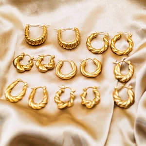 Collection of gold twisted hoop earrings with geometric textures on silk fabric