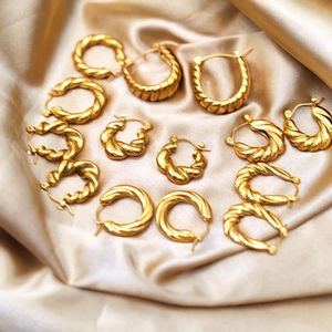 Detail showing 18K gold plated twisted croissant hoop earrings on champagne silk fabric