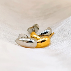 Macro shot of two-tone gold and silver water drop earrings on soft fabric