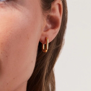 Polished gold U-shaped stainless steel earrings worn by a model in a close-up profile view