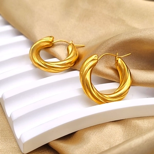 Detailed view of gold twisted hoop earrings with textured spiral design on silk