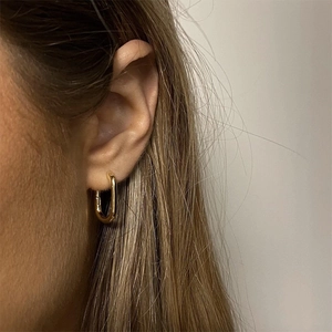 Polished gold U-shaped earring shown on model with minimalist stainless steel design