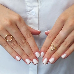 Minimalist gold geometric ring set with circular and triangular designs on model hand