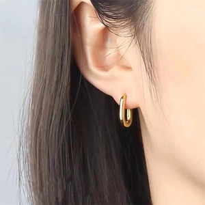 Close-up of elegant gold-tone U-shaped earrings on a model showing polished finish