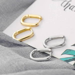 Polished gold and silver rectangular huggie hoop earrings on minimalist display card