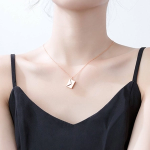 Close-up of rose gold envelope locket pendant on O-chain necklace worn by model