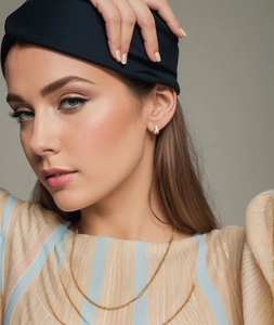Close-up of stylish gold teardrop stud earrings and thin necklace worn by a model