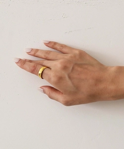 Close-up of a minimalist wide gold-plated stainless steel ring on a model hand