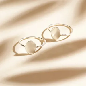 Macro detail of minimalist silver oval-shaped rings with smooth metallic finish and elegant shine