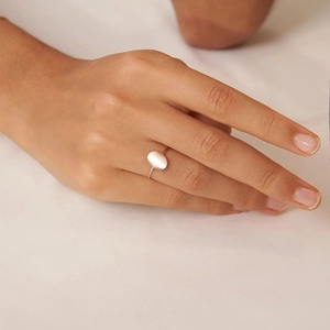 Detail showing an oval gemstone ring in rose gold finish on a model's finger
