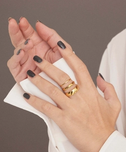 Close-up of three stacked minimalist gold-plated stainless steel rings on a model finger
