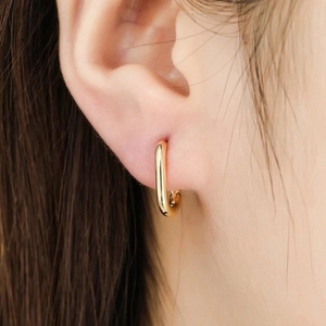 Detailed view of a polished gold U-shaped oval hoop earring worn on the earlobe