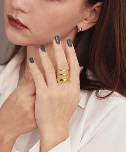 Polished gold stacking rings on fingers with matching minimalist jewelry and white shirt