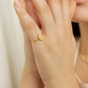 Close-up of minimalist gold plated oval signet ring worn on hand with a sleek finish