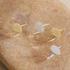 Macro view of minimalist oval gold and silver polished rings on a natural sandstone surface