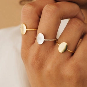 Close-up of minimalist gold and silver oval geometric rings worn on fingers