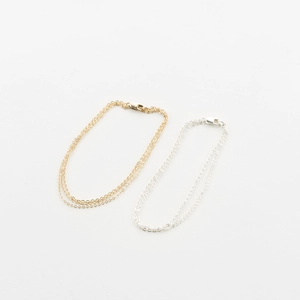 Detailed close-up of layered stainless steel chain bracelets in gold and silver finish