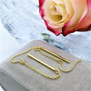 Detailed view of long gold-plated chain drop earrings on a grey velvet jewelry box