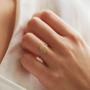 Detailed view of a minimalist gold-plated stainless steel oval ring on a model hand