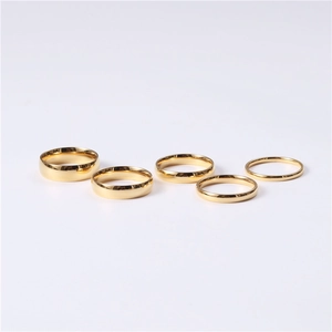 Detailed set of five polished gold stainless steel rings in various widths on white background