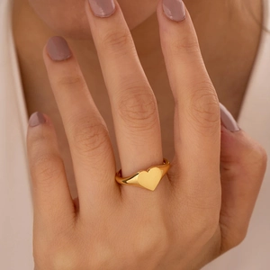 Gedetailleerde close-up van een minimalistische 18K vergulde hartzegelring om de vinger