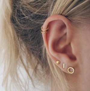 Detailed view of layered minimalist gold geometric stud earrings and ear cuffs on model