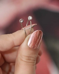 Detail of silver spiral earrings with round clear zircon and polished metal surface
