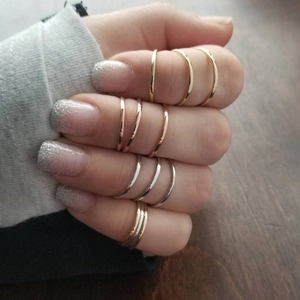 Minimalist stackable stainless steel rings in gold and silver finish shown on a hand